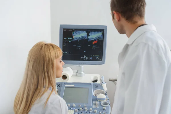 Two doctors looking at the ultrasonography divice — Stock Photo, Image