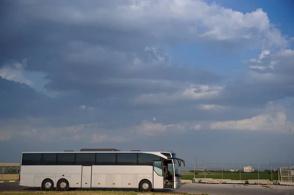 Autobus zatrzymujący się na parkingu pod błękitnym niebem z chmurami — Zdjęcie stockowe