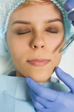 Top view of lips augmentation procedure on a young woman done by a cosmetologist doctor with Hyaluronic acid Injection.
