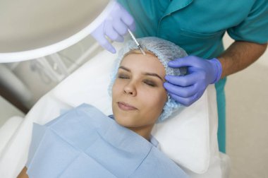 lateral view of elbow augmentation procedure on a young woman done by a cosmetologist doctor with Hyaluronic acid Injection.