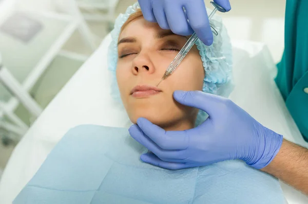 lateral view of lips augmentation procedure on a young woman done by a cosmetologist doctor with Hyaluronic acid Injection.