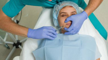 Top view of lips augmentation procedure on a young woman done by a cosmetologist doctor with Hyaluronic acid Injection.