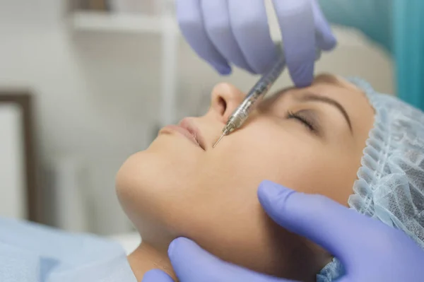 lateral view of lips augmentation procedure on a young woman done by a cosmetologist doctor with Hyaluronic acid Injection.