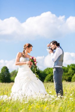Evlilik çift çayır üzerinde fotoğraf çekmek