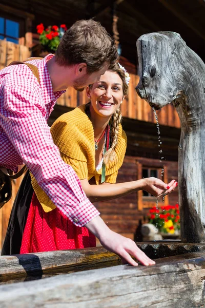 Par på mountain hut dricksvatten från källa — Stockfoto