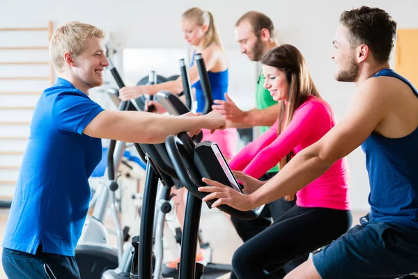 Grupo de hombres y mujeres haciendo entrenamiento cardiovascular en el gimnasio —  Fotos de Stock