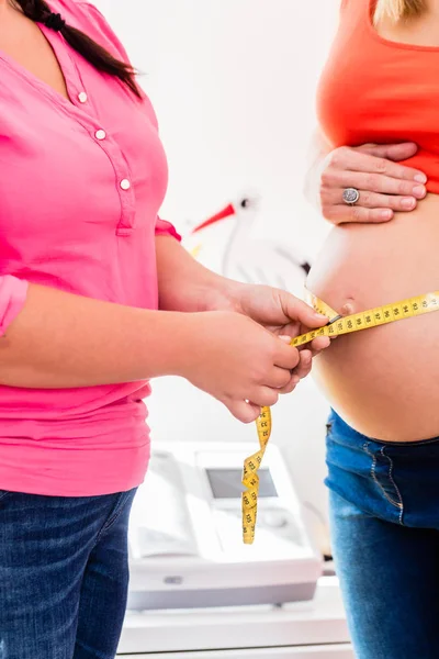 Mujeres embarazadas de pie y partera que miden la circunferencia — Foto de Stock