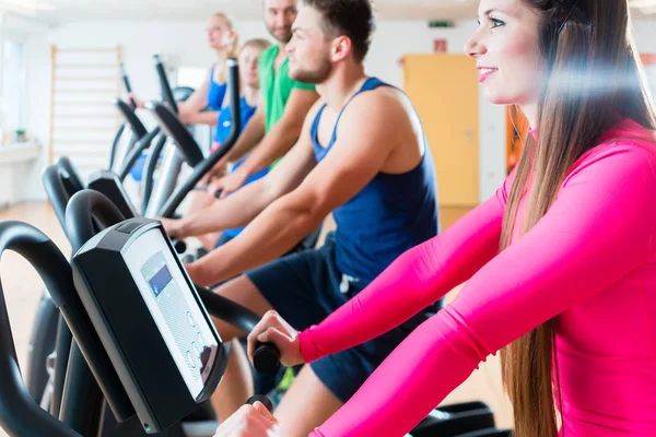 Hombres y mujeres en bicicletas de cardio en el gimnasio — Foto de Stock