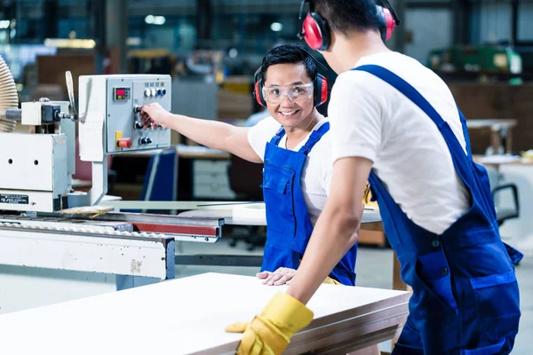 Marangozlukta iki ahşap işçisi tahta kesiyor