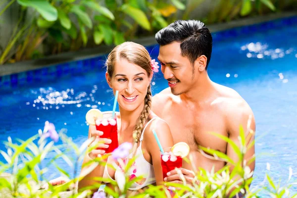 夫妇在喝鸡尾酒的亚洲酒店游泳池 — 图库照片