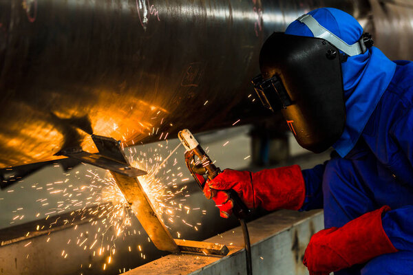 Сварщик на заводе сварки металлических труб

