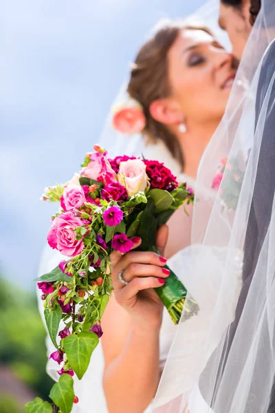 Par de noivas beijando sob véu — Fotografia de Stock