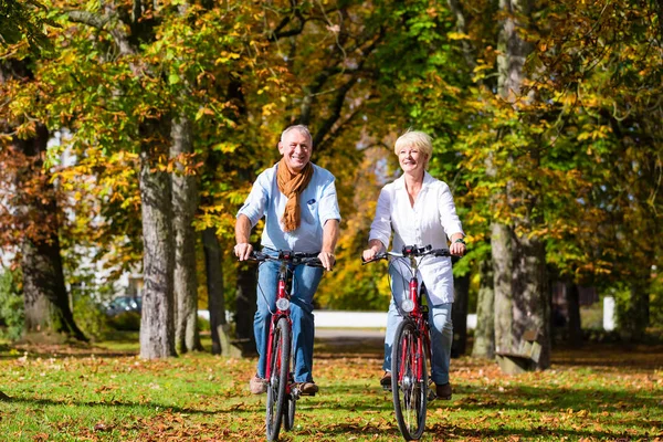 Idosos em bicicletas tendo passeio no parque — Fotografia de Stock