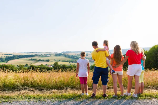 Rodzina spożywająca spacerem patrząc na krajobraz ich domu — Zdjęcie stockowe