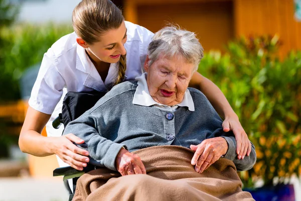 Senior vrouw in verpleeghuis met verpleegster in tuin Stockfoto