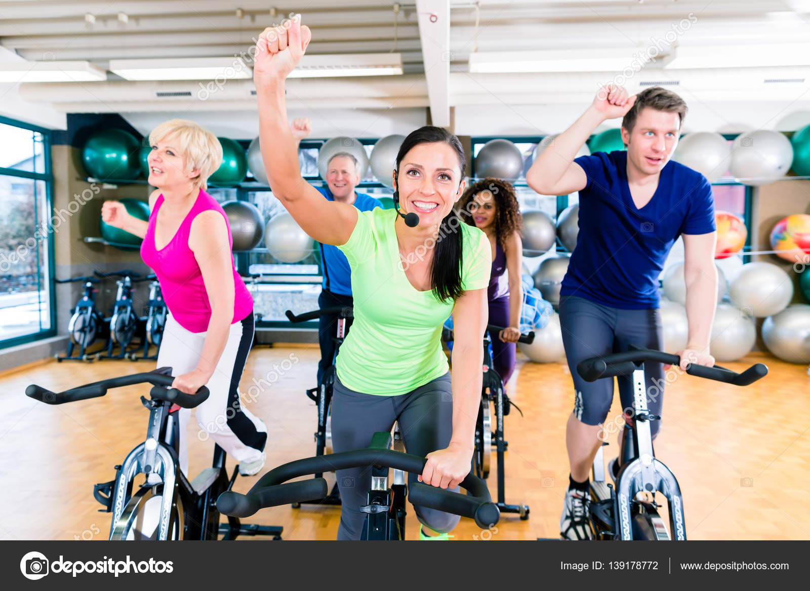 Group of men and women spinning on fitness bikes in gym — Stock Photo