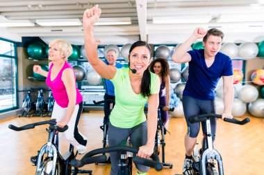 Grup salonunda fitness bisiklet üzerinde iplik kadın ve erkek