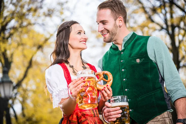 Pareja en Dirndl y Tracht teniendo Pretzel y Bier —  Fotos de Stock