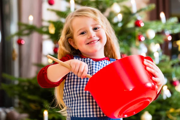 Κορίτσι ψήσιμο τα cookies, μπροστά από το χριστουγεννιάτικο δέντρο — Φωτογραφία Αρχείου