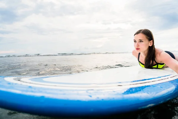 Girl surfer paddling on surfboard to the open sea — Stock Photo, Image