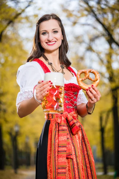 Flicka klädd Dirndl med kringla och öl mugg — Stockfoto