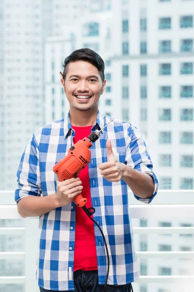 Junger indonesischer Mann mit Bohrmaschine — Stockfoto