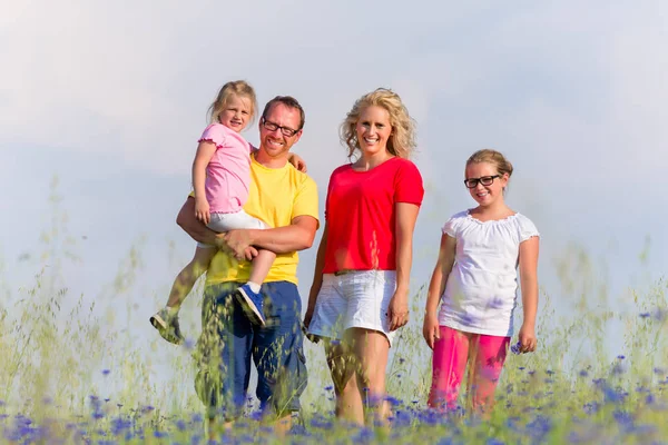Familie steht im Sommer mit Blumen auf der Wiese — Stockfoto