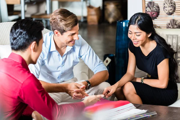 Couple with salesman in furniture store — Stock Photo, Image