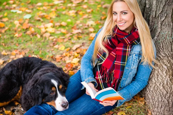 Mulher com cão livro de leitura no parque de outono — Fotografia de Stock