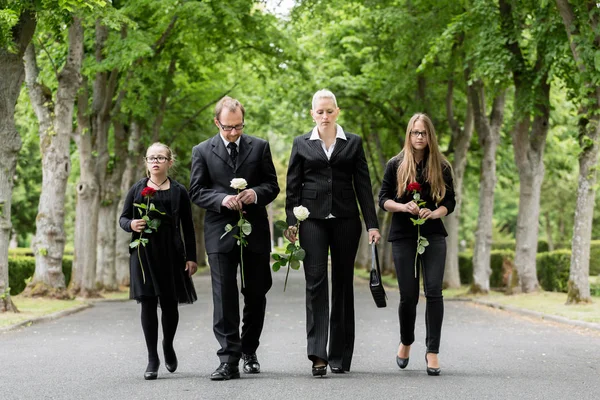 Семья идет по аллее на кладбище — стоковое фото