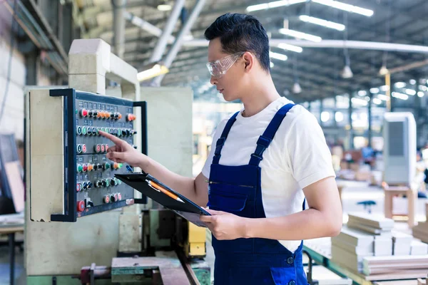 Worker pressing buttons on CNC machine in factory — Stock Photo, Image