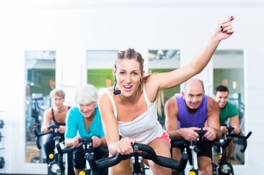 Spor salonunda fitness bisiklet üzerinde iplik üst düzey insanlar