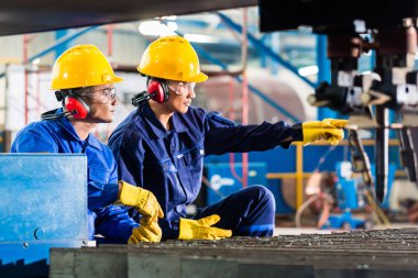 Endüstriyel metal kesme makinası fabrikasında işçi