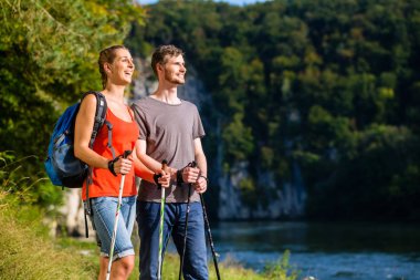 Man and woman hiking at river in summer clipart