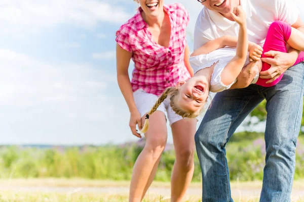 Familie tobt auf Feld mit Eltern, die Kind tragen — Stockfoto