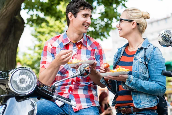 Couple touristique se reposer pendant la visite en scooter manger currywurst — Photo