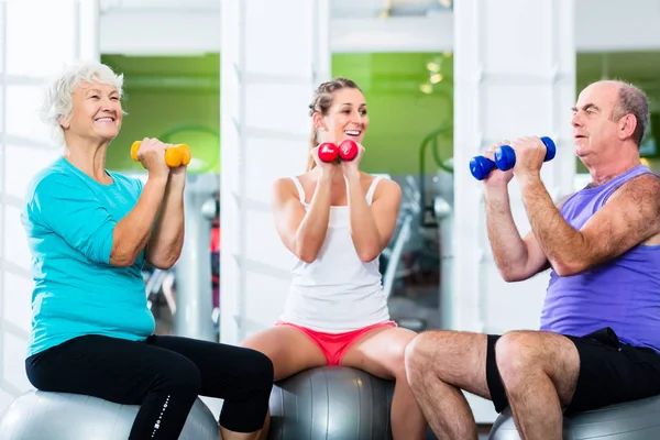 Anziani con allenatore in palestra a sollevamento pesi sportivi — Foto Stock