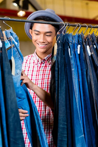 Aziatisch mens browsen jeans in mode winkel — Stockfoto