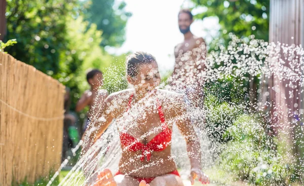 Familjen nedkylning med sprinkler i trädgården — Stockfoto