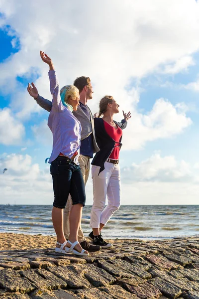 Amigos desfrutando do pôr do sol na praia — Fotografia de Stock
