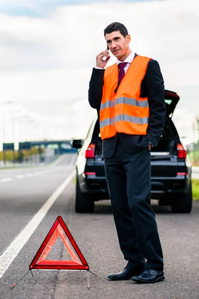 車の故障の警告の三角形を建てる男 — ストック写真