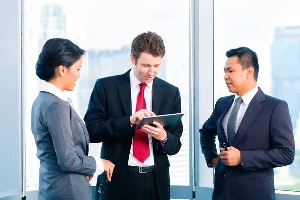 Businesspeople standing at office windo working — Stock Photo, Image