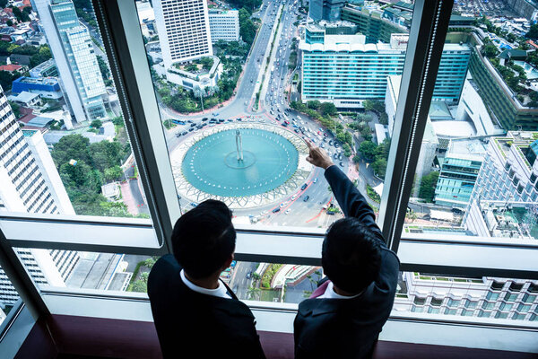 Two Asian businesspeople looking down to city streets