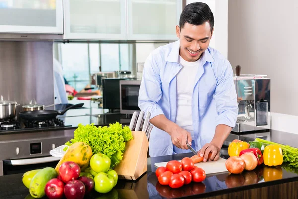 Pria Asia memotong salad di dapur — Stok Foto