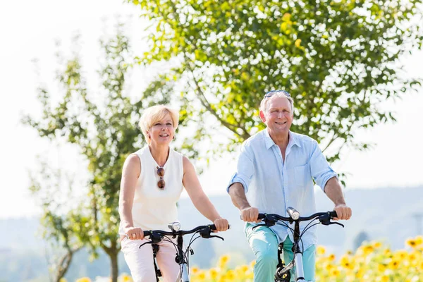 Ηλικιωμένο ζευγάρι, γυναίκα και άντρας, κάνουν ποδήλατο. — Φωτογραφία Αρχείου
