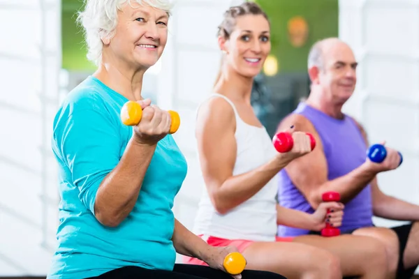 Seniorzy z trenerem w siłowni hotelu sport podnoszenia brzana — Zdjęcie stockowe