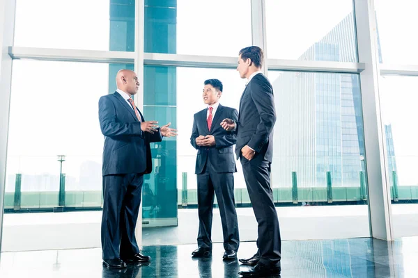 Drie zakenmensen die permanent in de lobby van het kantoor — Stockfoto