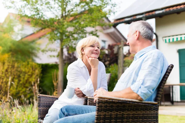 Senior man and woman sitting in front of house — Stock Photo, Image
