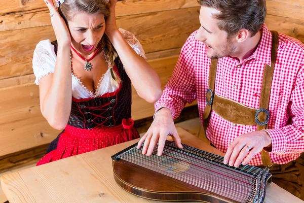 Homem jogando mal em zither na cabana da montanha — Fotografia de Stock