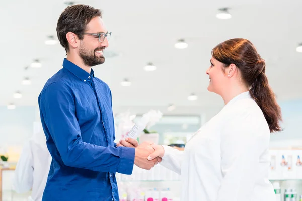 Hombre en la farmacia con las ventas dama de compras — Foto de Stock